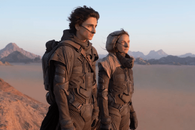 When is Dune leaving Netflix? A still image from Dune (2021) features Paul Atreides (Timothée Chalamet) and Lady Jessica (Rebecca Ferguson) standing on a cliff, overlooking a desert landscape.