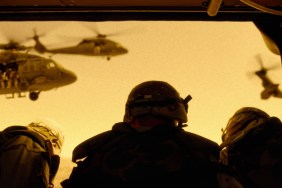 A group of soldiers look at helicopters in the sky.