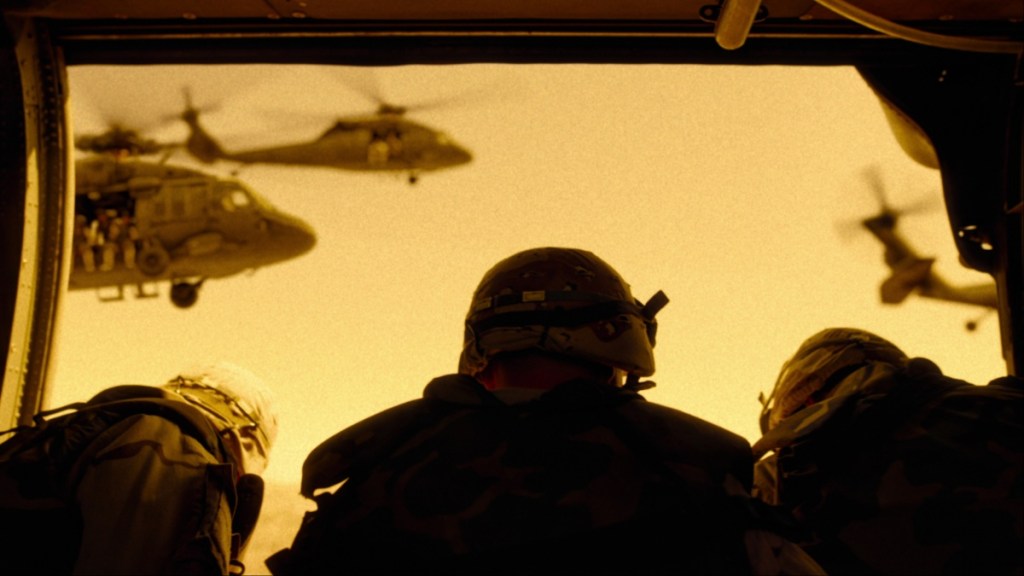 A group of soldiers look at helicopters in the sky.