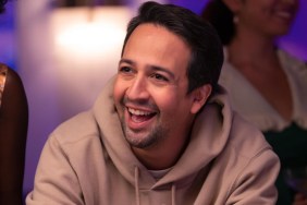 Lin-Manuel Miranda sits at a table and smiles in Percy Jackson.